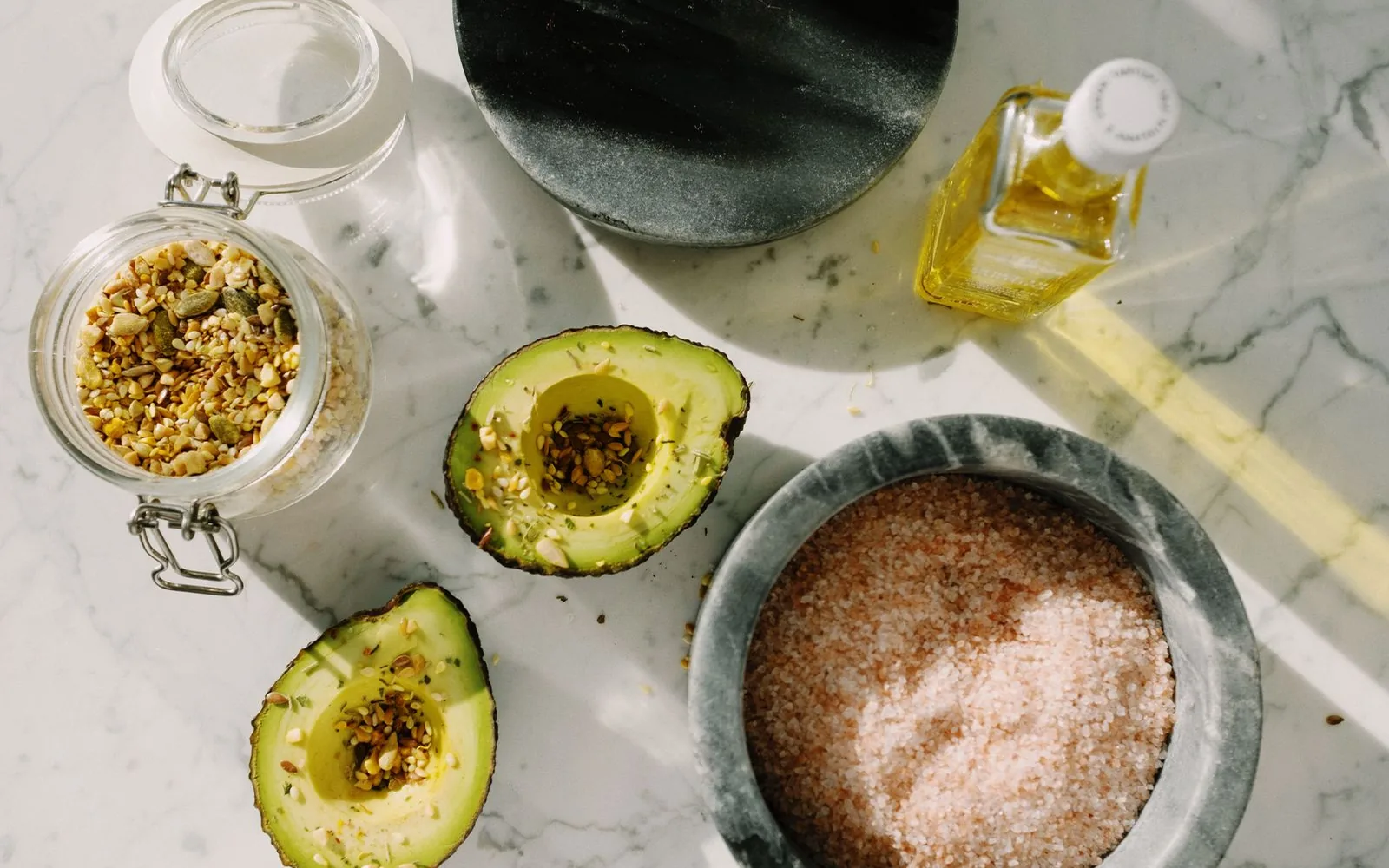 Aguacate y semillas sobre una encimera de mármol