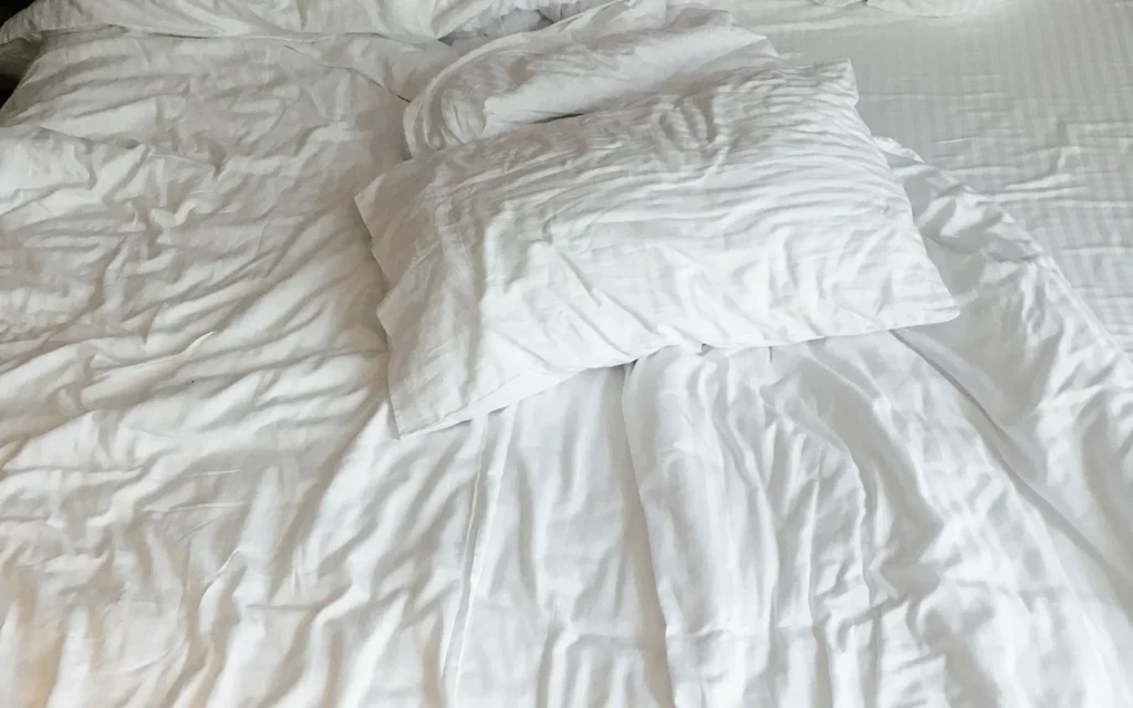 Cama con almohada y sábanas blancas